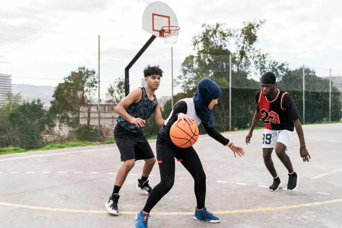 Jeunes qui jouent au basketball sur un terrain extérieur